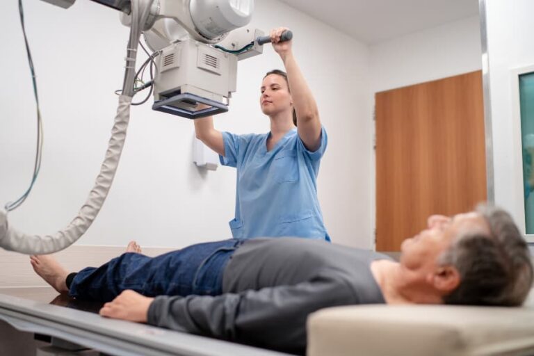 Medical technician conducting X-ray examination on patient’s leg in medical clinic