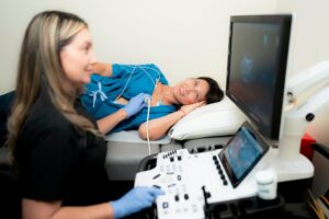 Cardiac sonographer performing ultrasound on patient